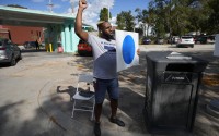 Shawn Steward reacts to a passing vehicle during a blue dot campaign sign get-together, Tuesday, Sept. 24, 2024, in Omaha, Neb. The blue dot signs, spotted throughout Omaha, represent Democratic-voting households in a state surrounded by Republican red. 
(Charlie Neibergall / AP Photo)