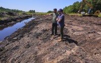 Cranberry grower Jarrod Rhodes points out to engineer Robert Kennedy (right) the path of water flow at a cranberry bog being restored to a natural habitat at the South Meadow Bogs, Thursday, Aug. 7, 2025, in Carver, Mass. 
(Charles Krupa / AP Photo)