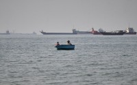 Two men sit in a small boat on the water as a mix of bulk carriers, cargo ships, and service vessels line the horizon in the Strait of Hormuz off Bandar Abbas, Iran, Monday, April 27, 2026.
(Razieh Poudat / ISNA via AP)