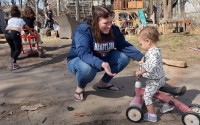 Day care operator Shannon Hampson encourages 14-month-old Imani Swindell as she pilots a scooter on Monday, March 24, 2025, at Hampson's home-based business Wild Child Daycare in Lincoln.  
(Eric Gregory / Flatwater Free Press)