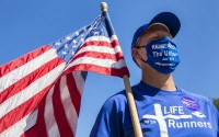 LIFE Runner founder Pat Castle listens to Gov. Pete Ricketts during a ceremony to sign the LB 814 bill at the steps of the state capitol in Lincoln, on Saturday, Aug. 15, 2020. The anti-abortion bill bans dismemberment abortion in Nebraska. (Kenneth Ferriera/Lincoln Journal Star via AP)
