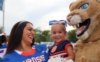 Katya Kohut beams while being held by one of the Gross Catholic cheerleaders, Gabby Hunter and mascot Freddie Cougar, at the school’s homecoming pep rally. 
(Susan Szalewski / The Catholic Voice)
