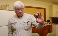 Mike Matthews holds a vial he uses when testing for nitrate in water on December 1. Each test costs $16. There are 37 reverse osmosis, or RO, systems to test in town. Prosser is one of many towns grappling with the costs of trying to remove nitrate from their water supply – roughly 10 percent of Nebraska communities have tested nitrate levels higher than the federal standard at least once since 2010. (<a href="https://flatwaterfreepress.org/author/acostello/">Laura Beahm</a> / Flatwater Free Press)