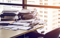 Messy piles of paper sit on a desk. Each year, thousands of people are sued and don’t participate in their lawsuit. For some, this is because they were never notified, or the documents they received were difficult to understand.
(Shutterstock)