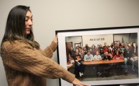 Tessa Domingus holds up a staff photo from 2020 to show the growth of the Mental Health Association of Nebraska. The nonprofit has grown from a few employees to more than 70 when fully staffed, she said.
(Ryan Hoffman / Flatwater Free Press)