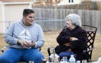 Zak Abughalyoon, 19 (left) and St. Pius X Catholic Church of Omaha parishioner Rosie Volkmer chat over tea outside the Abughalyoon family home in Papillion on Wednesday, Feb. 26, 2025.  "The U.S. made a promise to them,” said another St. Pius parishioner. “And we broke our promise." 
(Rebecca S. Gratz / Flatwater Free Press)