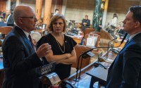 From left: State Sens. John Arch of La Vista, Machaela Cavanaugh of Omaha and Ben Hansen of Blair meet on the floor of the Nebraska Legislature. Arch is speaker of the Legislature on Jan. 15, 2025. 
(Zach Wendling / Nebraska Examiner)