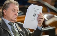 State Sen. Stan Clouse of Kearney reads the voter initiative packet from 2022 that led to voter-approved increases to the state’s minimum wage, March 31, 2025. 
(Zach Wendling / Nebraska Examiner)