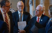  University of Nebraska Dr. Jeffrey Gold (right) speaks with state senators and NU regents after a forum with dozens of Nebraska state senators regarding NU’s proposal to buy out the share of Nebraska Medicine owned by Clarkson Regional Health Services. (At center) is Dr. Bill Lydiatt, Clarkson’s CEO, and (at left) is State Sen. Mike Jacobson of North Platte, Jan. 14, 2026.  (Zach Wendling / Nebraska Examiner)
