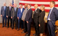 The justices of the Nebraska Supreme Court join Nebraska Gov. Jim Pillen (center left in a blue suit) and Lt. Gov. Joe Kelly (far left) for the elevation of Douglas County District Judge Derek Vaughn (center) to the Supreme Court. Vaughn’s colleagues, from left: are Justice John Freudenberg, Jason Bergevin, Jeffrey Funke (chief), William Cassel, Stephanie Stacy and Jonathan Papik, Nov. 10, 2025. 
(Zach Wendling / Nebraska Examiner)
