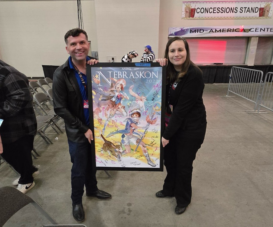 Executive Director of NAMI Nebraska, James Michael Bowers (left) holding up the highest value item sold at the NAMI Charity Auction, bought by Nebraskon Convention Chair Becky Potter (right), for $1000.<br />(Austin Petak / The Daily Record)